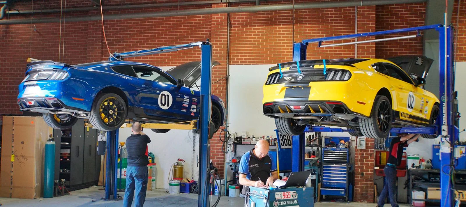 Ford mustangs on floor lift in mechanic shop